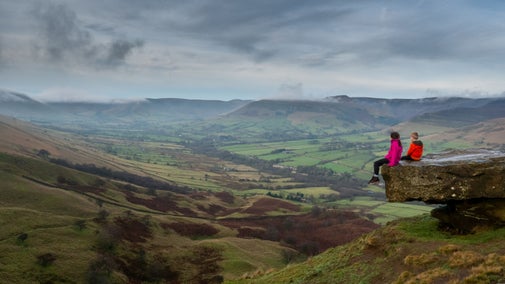 Two children sitting on the big stones at Back Tor, Edale, Derbyshire overlooking the stunning view.